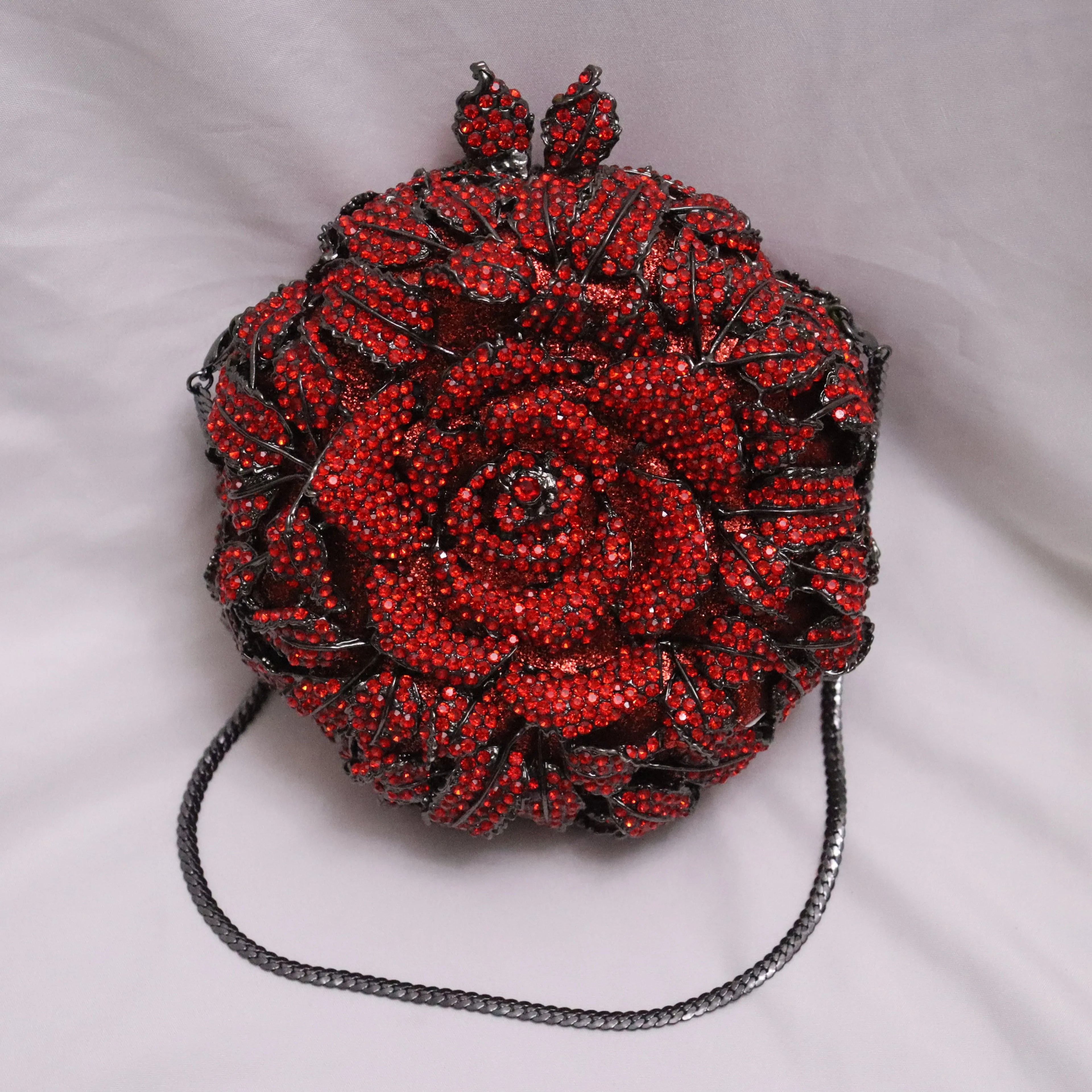 Red rose-shaped crystal designer evening clutch bag with black metal chain strap, perfect for weddings and formal events.