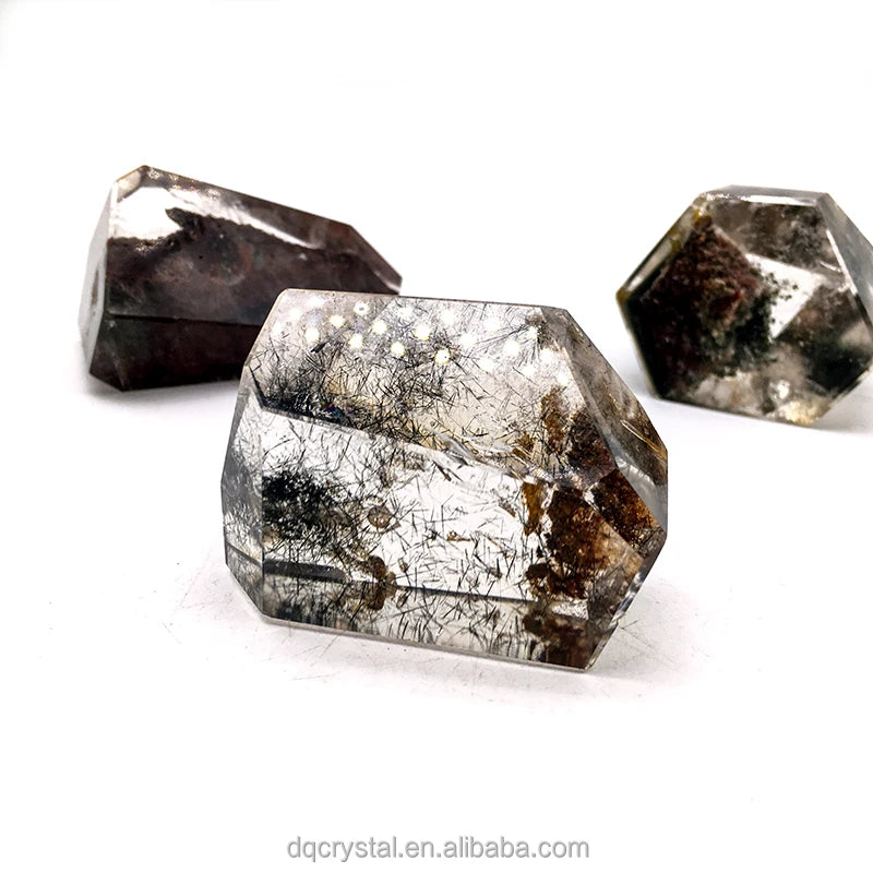 Silvery quartz crystal freeform with dark needle-like inclusions, faceted prism