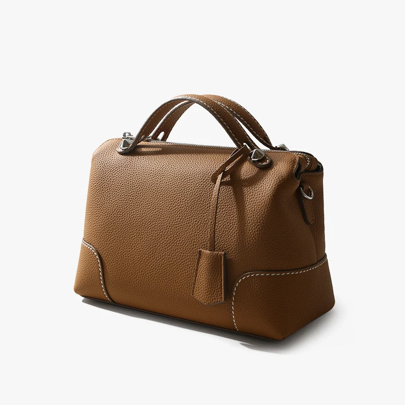 Tan pebbled top-grain cowhide designer handbag with white stitching and silver hardware accents.