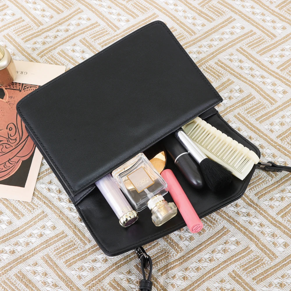 Black genuine cow leather designer crossbody handbag with flap, containing makeup, perfume, and a comb.