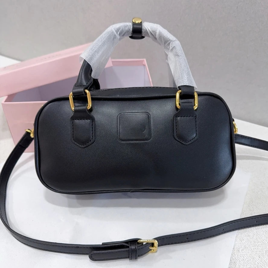Black leather trunk handbag with gold hardware, top handles, and adjustable shoulder strap for women.