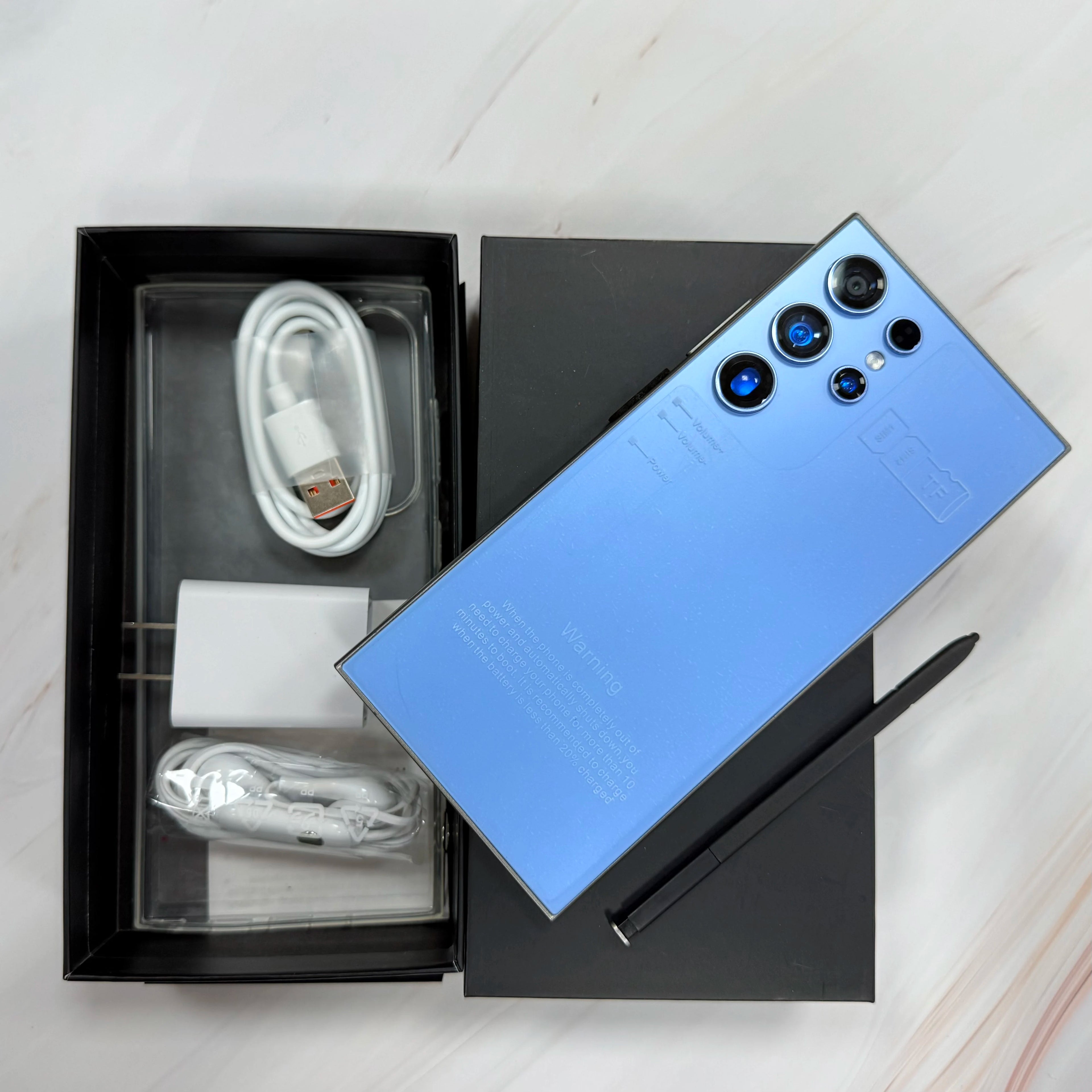 Blue smartphone with cables and charger in open retail box.