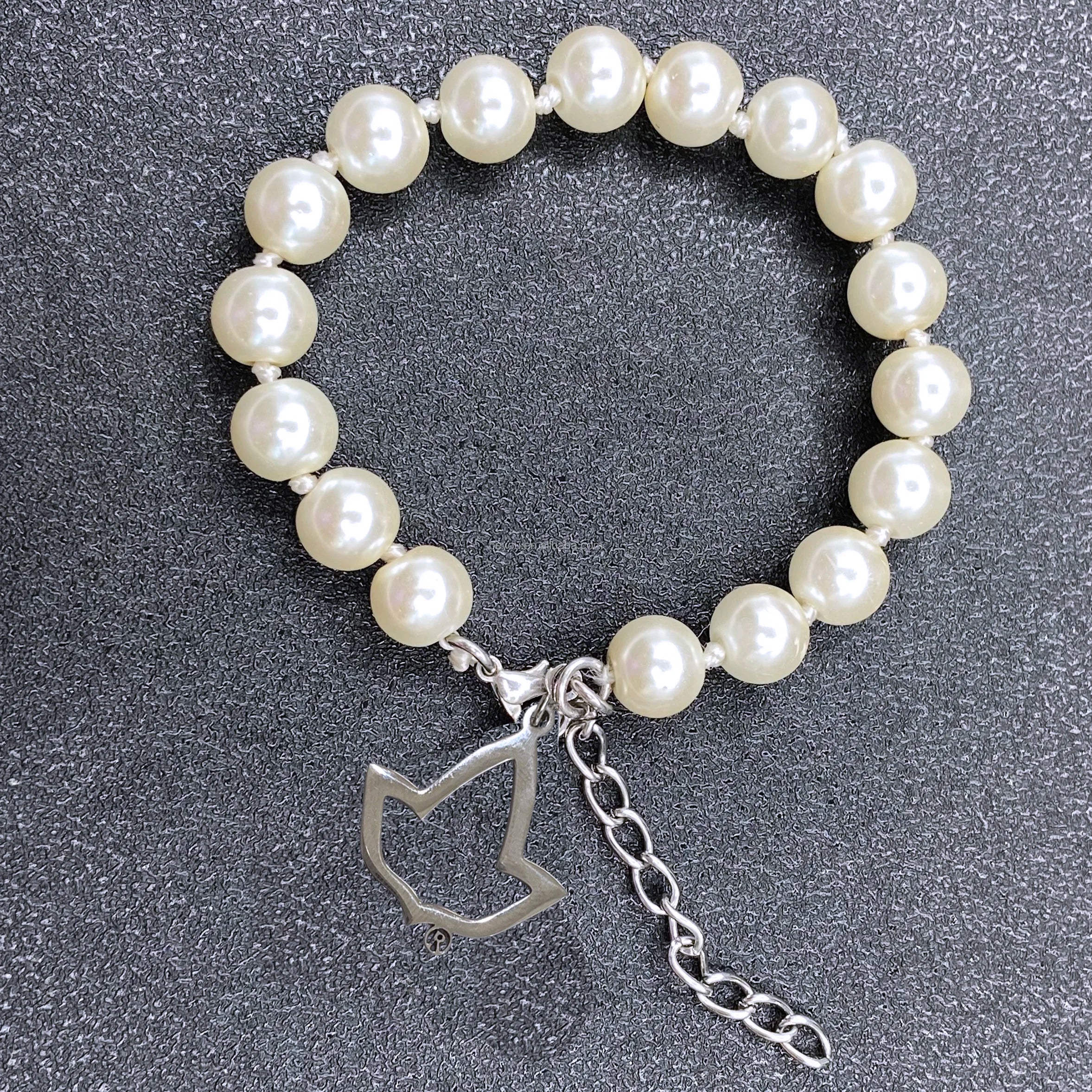 White pearl bracelet for luxury designer handbags with silver leaf charm and adjustable extension chain.