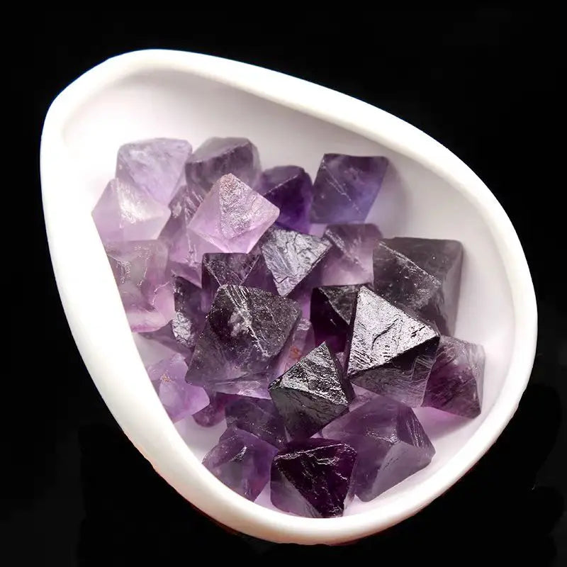 Purple rough crystal octahedra in white dish, densely packed translucent facets
