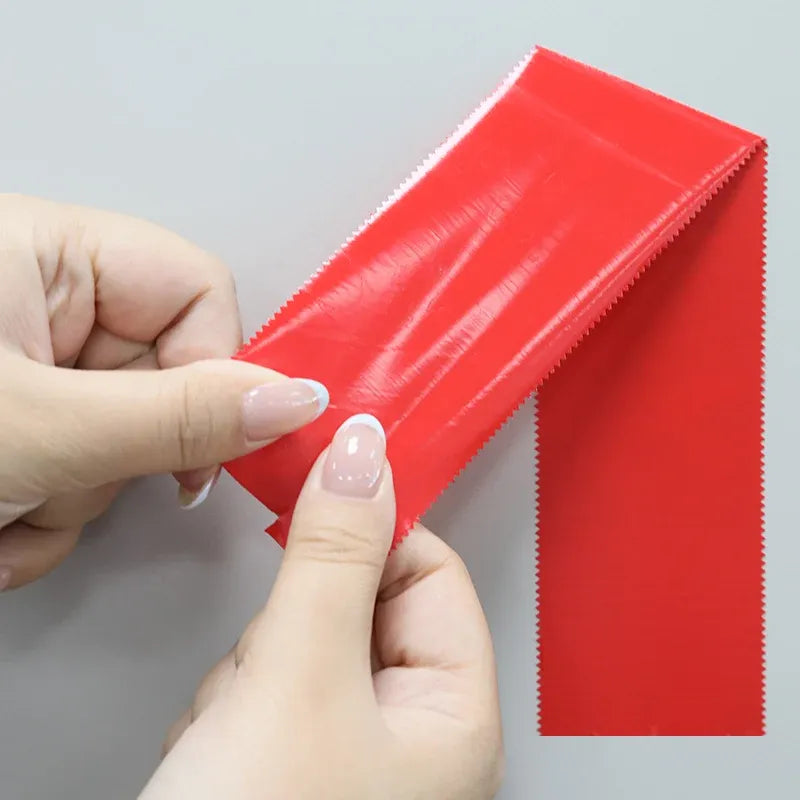 Applying red adhesive tape to a surface, strip being smoothed by hands