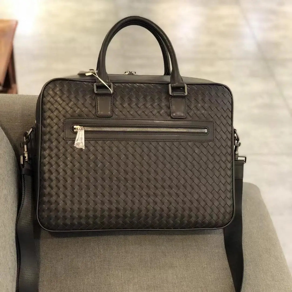 Luxury black hand-woven cowhide leather laptop briefcase for men with a zip front pocket and adjustable shoulder strap.