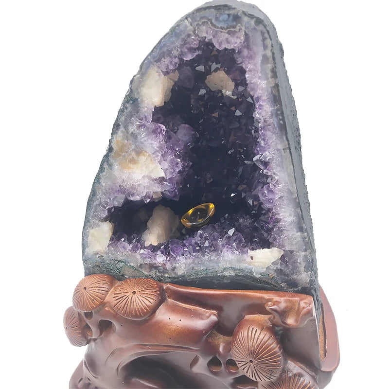 Purple amethyst geode with a small yellow light in the hollow, set in a carved brown base