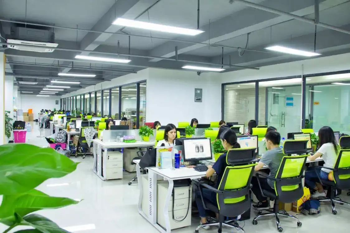 Factory office production floor with workers seated at computers at workstations