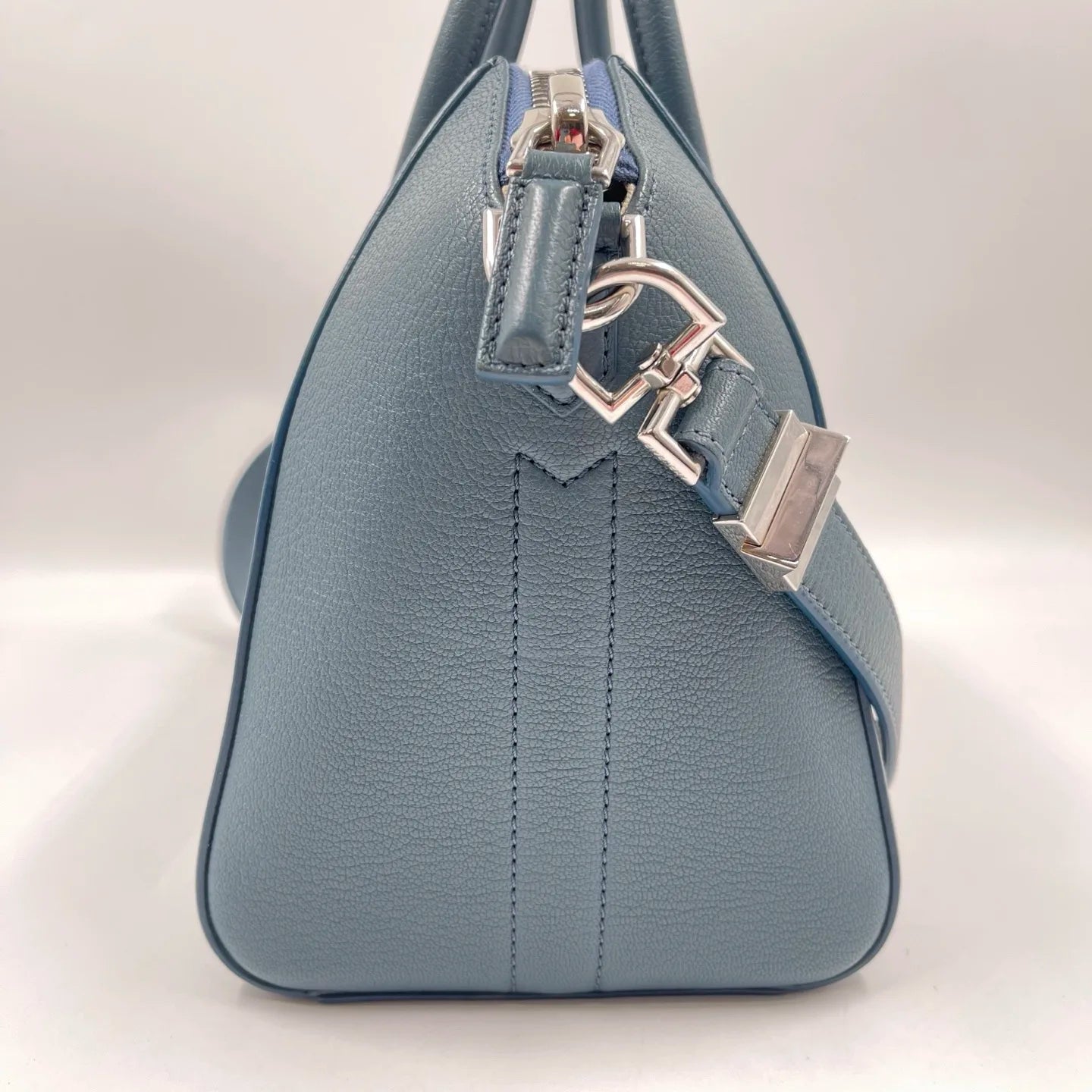 Blue pebble-grain leather designer tote bag with silver hardware, zippered closure, and adjustable shoulder strap.