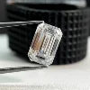 Emerald-cut diamond solitaire on a dark band, small close-up with sparkle facets.