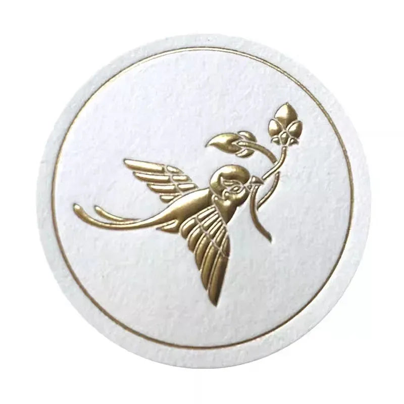 White round sticker label with gold angel figure logo, embossed.