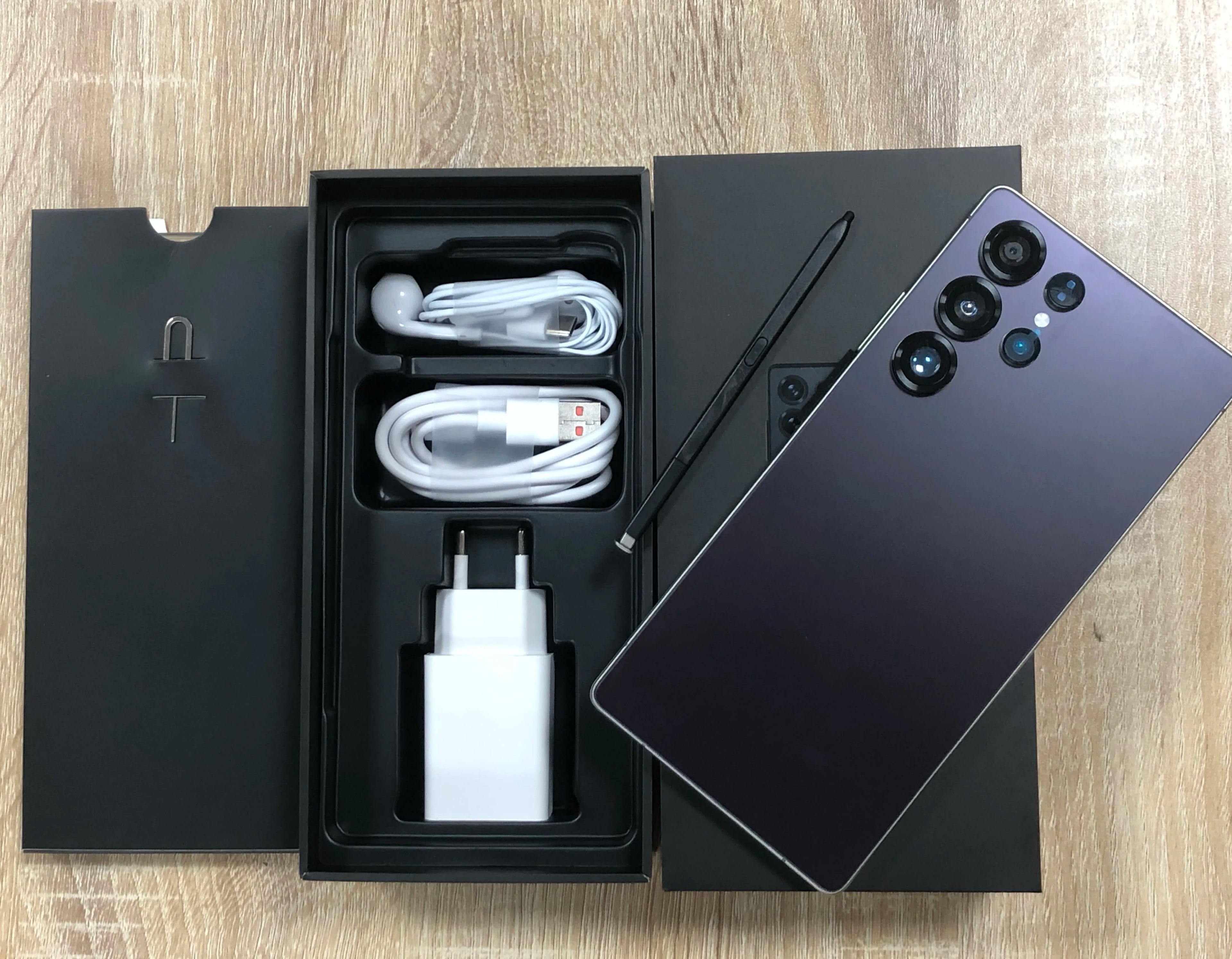 Android smartphone with dark blue back and quad rear cameras; box with cable and charger