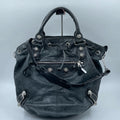 Pre-owned black leather designer bucket bag with metal studs, top handle, zip pocket, and adjustable shoulder strap.