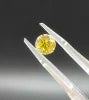 Fancy intense yellow round diamond gemstone on silver tweezers