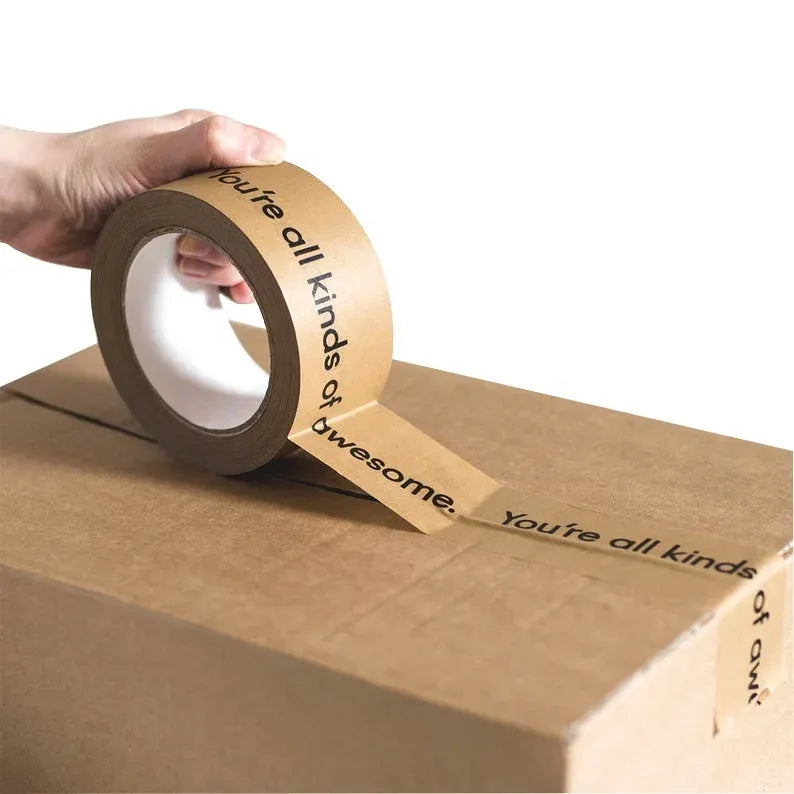 Brown kraft paper packing tape roll held by hand, wide pressure-sensitive adhesive tape