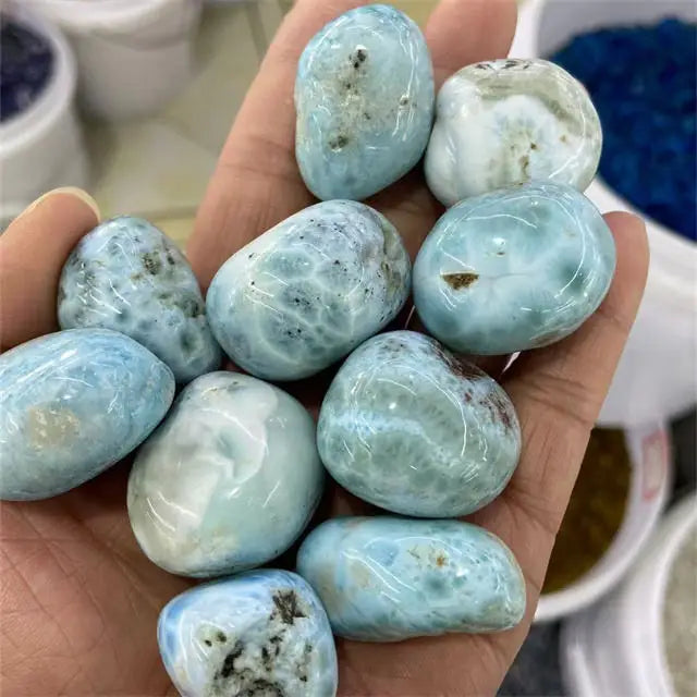 Sky blue tumbled larimar gemstone stones in a hand, smooth rounded polished finish
