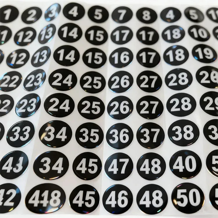 Macro view of self-adhesive round number stickers, black circles with white numerals 1–50