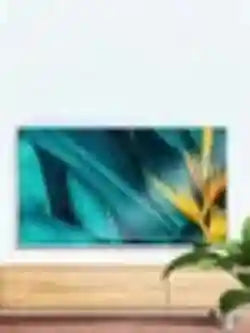 Flat-screen TV mounted on a wall above a light wood media console displaying a teal and yellow abstract image.