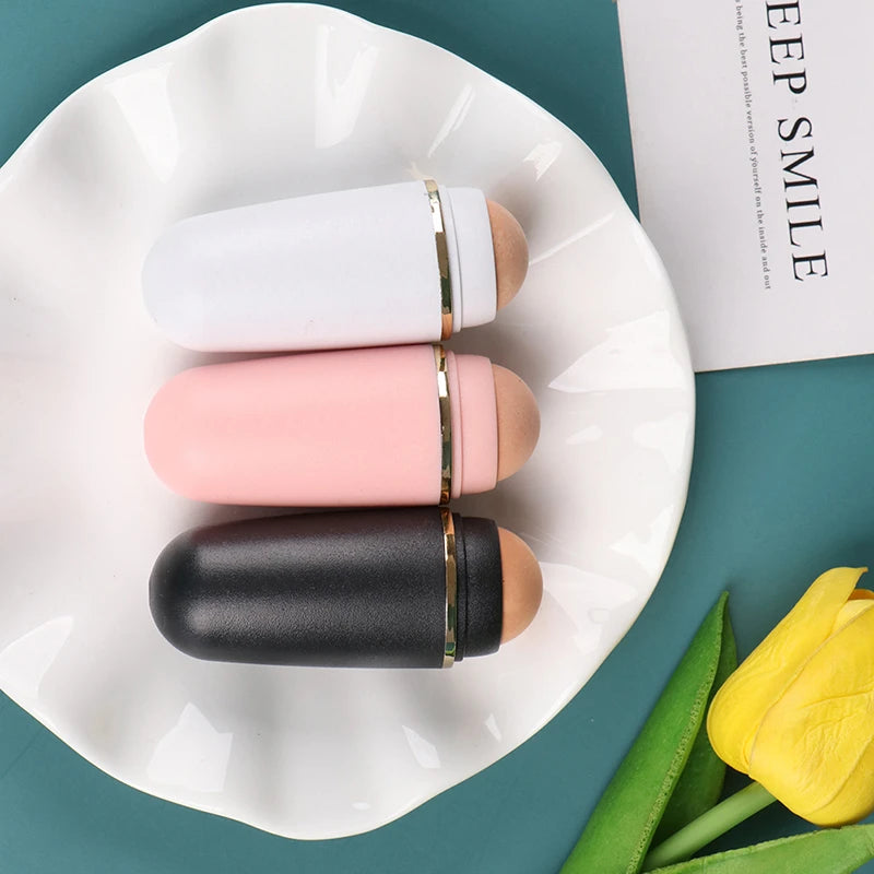 Three volcanic stone oil-absorbing facial rollers in white, pink, and black, displayed on a white ruffled plate.