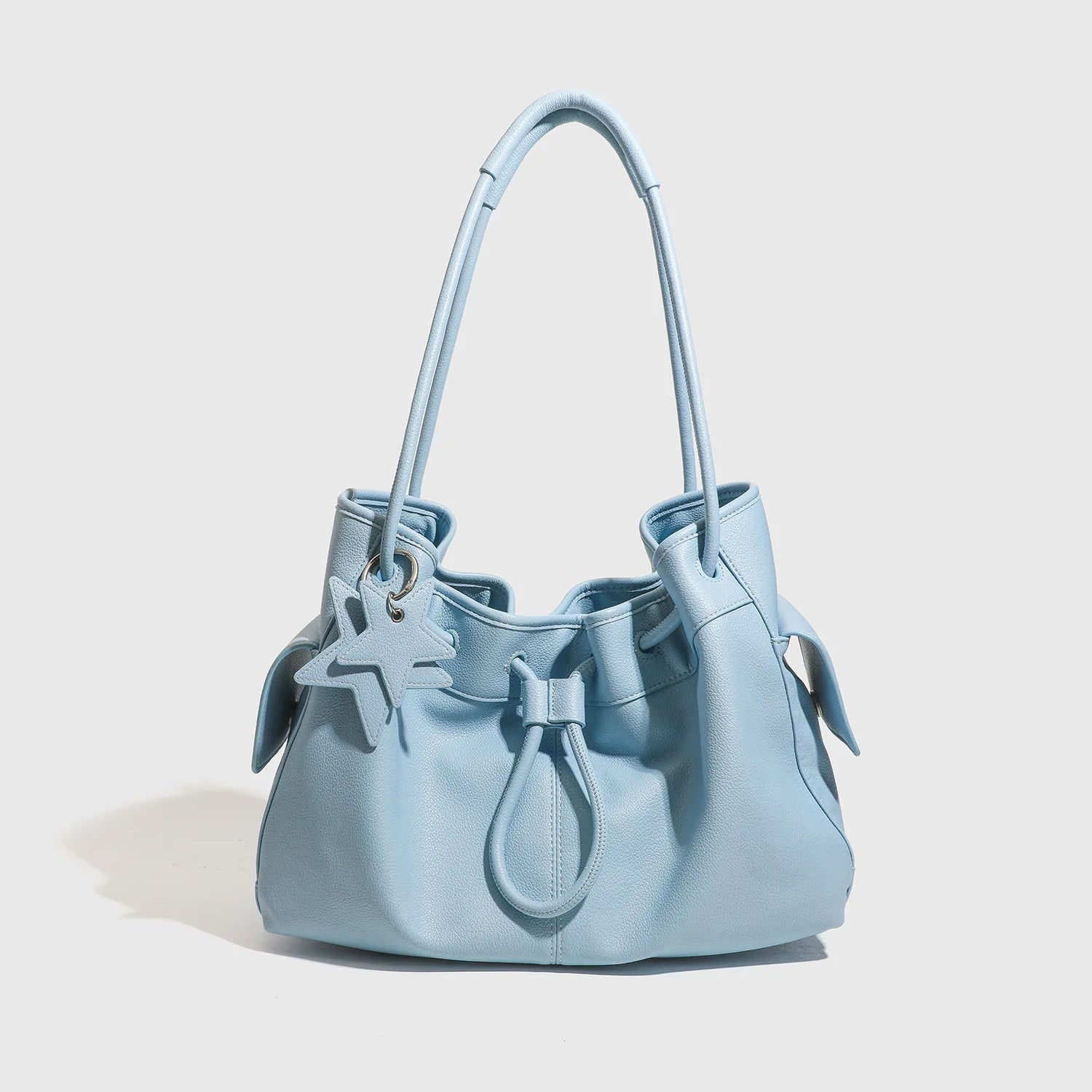 Light blue designer shoulder bag with slouchy silhouette, star charm, and dual straps for commuting.
