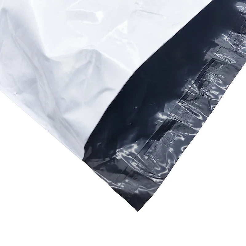 Poly shipping bag close-up: white plastic with glossy black panel and sealed seam.