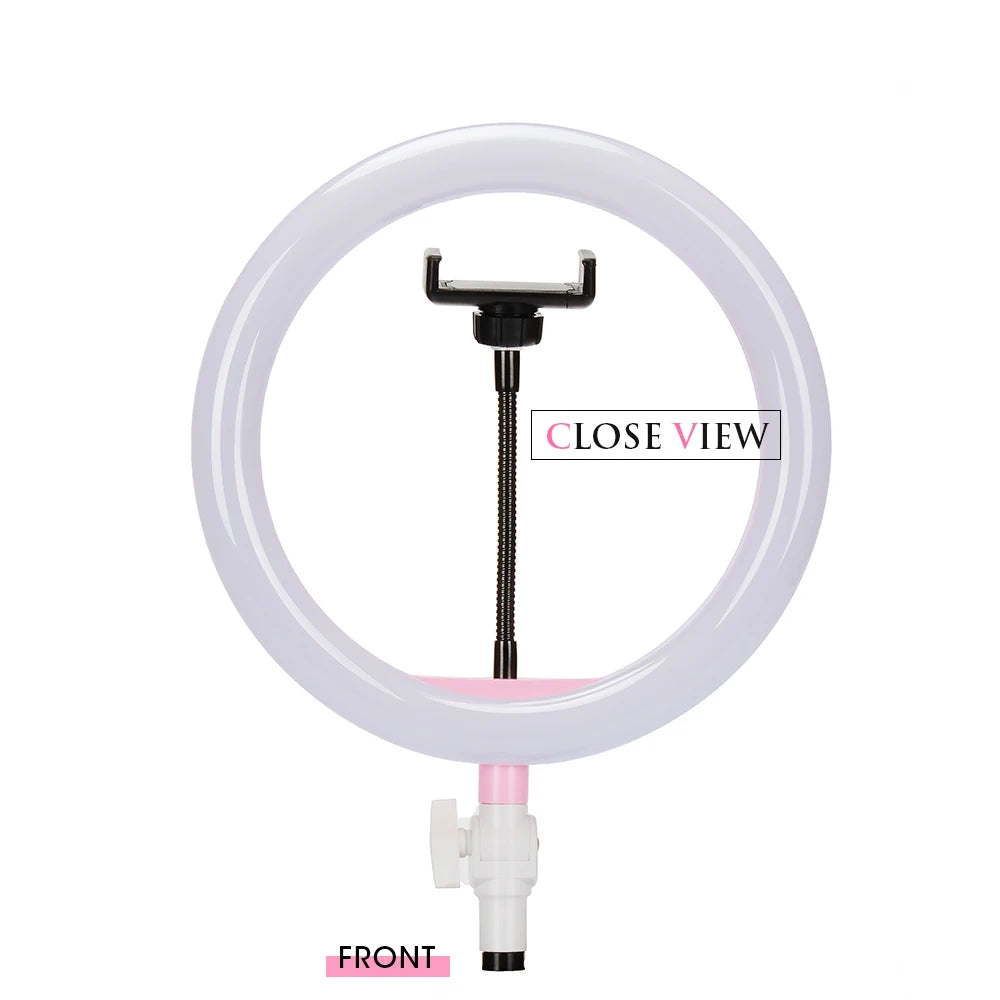 White circular LED ring light with a central flexible phone holder mount, set on a pink and white plastic base.