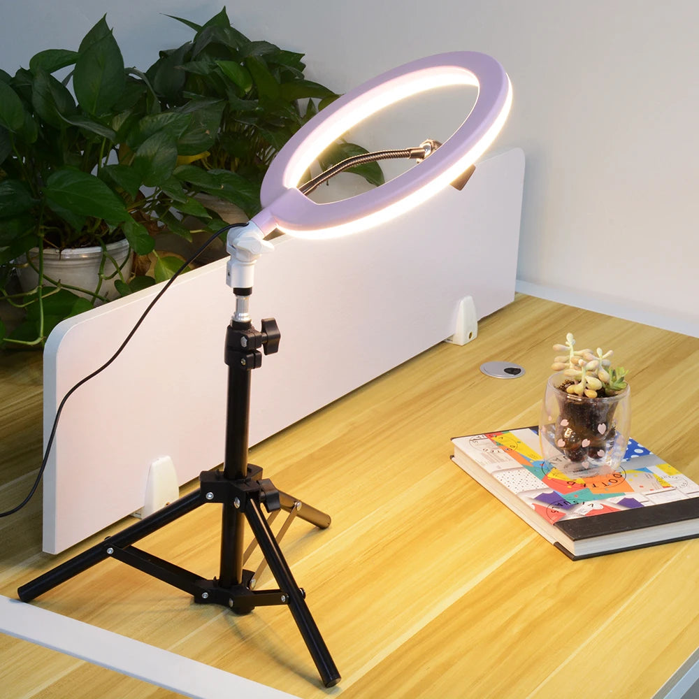 Light purple ring light on a black adjustable tripod stand, used for desktop lighting and video recording.
