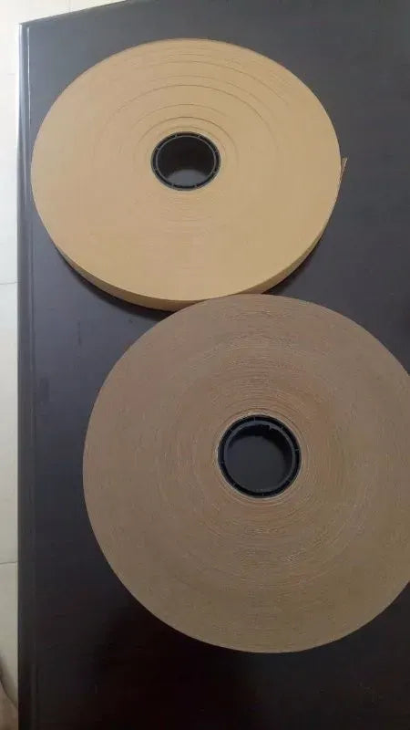 Beige hot melt glue tape rolls on a surface, single-sided adhesive, core holes visible