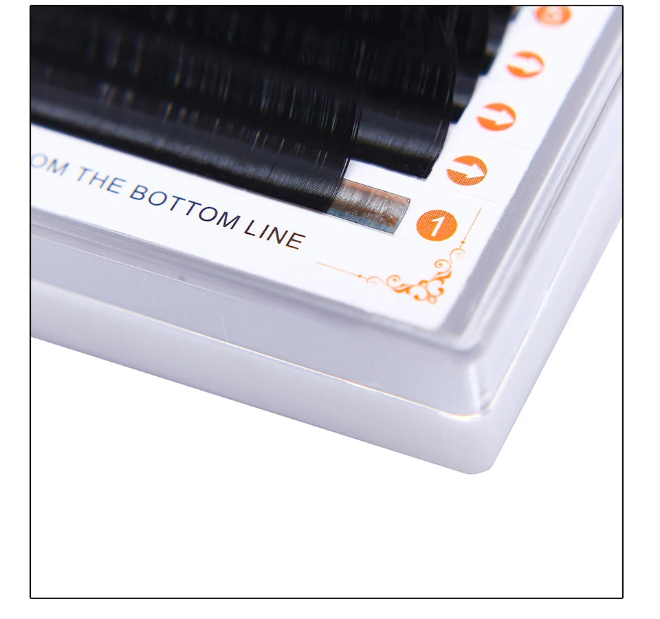 Black false eyelash extension strips arranged in a white plastic storage tray for professional application.