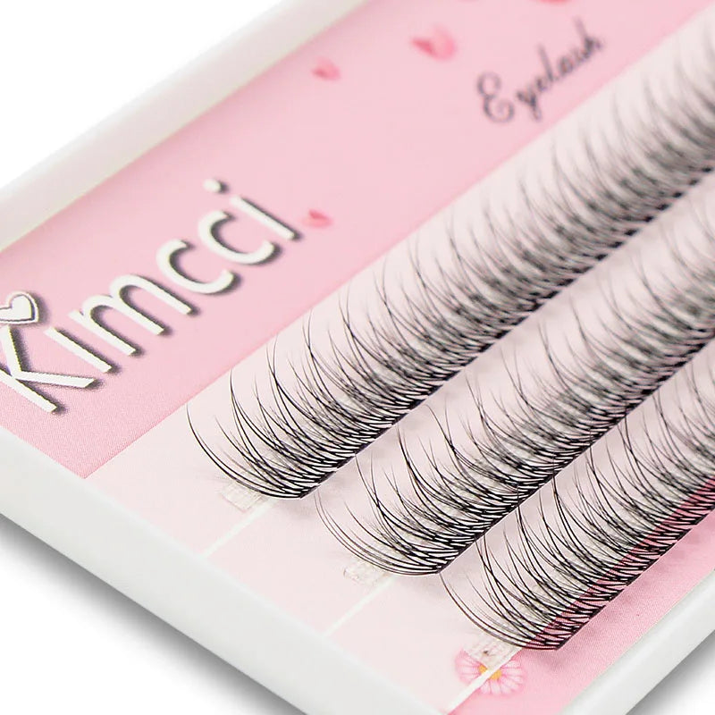 Black mink individual flared eyelash extension clusters arranged in rows on a pink Kimcci branded tray.