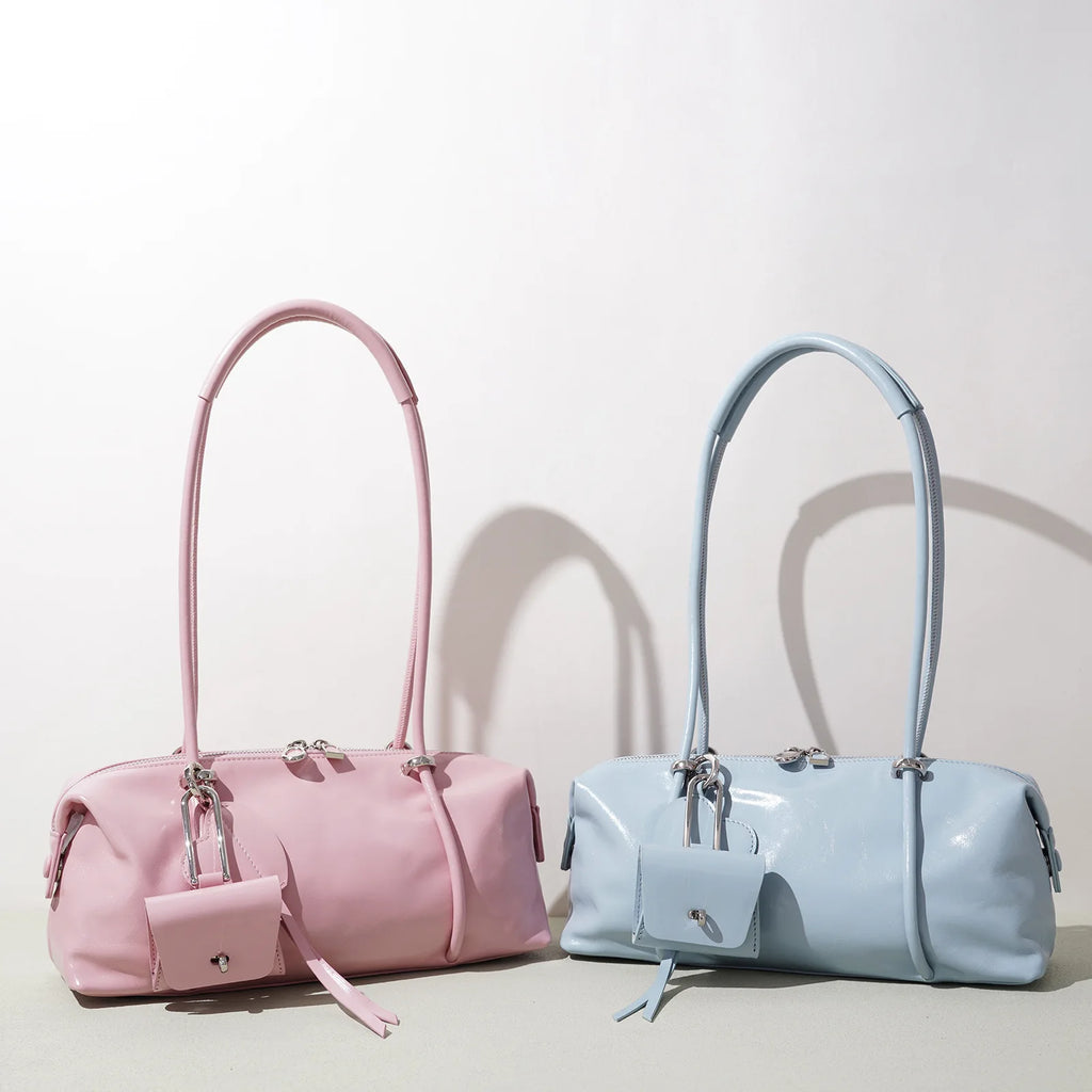 Pink and light blue minimalist Boston underarm bags with luxe glossy texture, silver hardware, and matching charm.