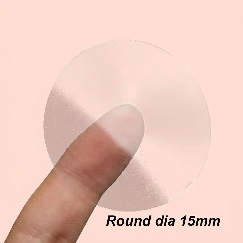 Clear round vinyl label sticker, 15mm diameter, held by fingertip