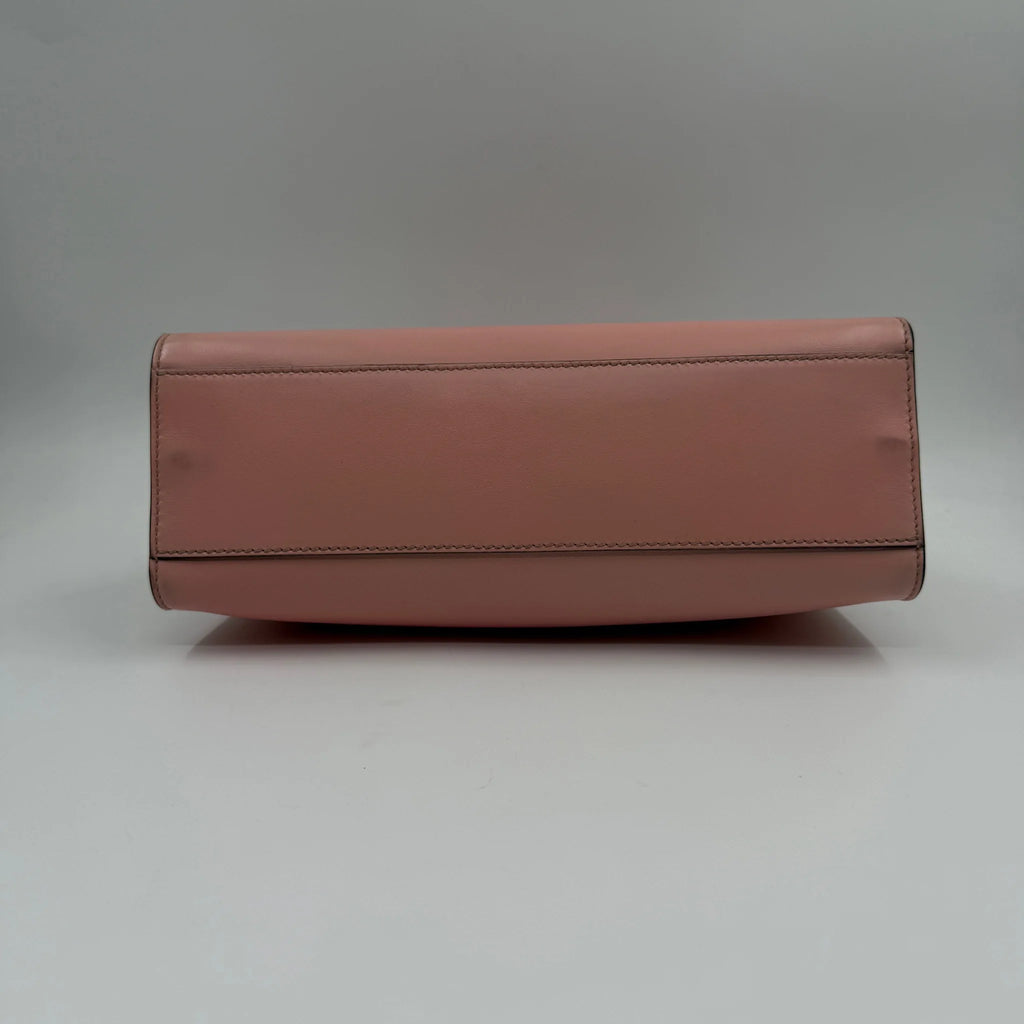 Bottom view of a luxury pre-owned pink leather designer crossbody bag with a flat, structured base.