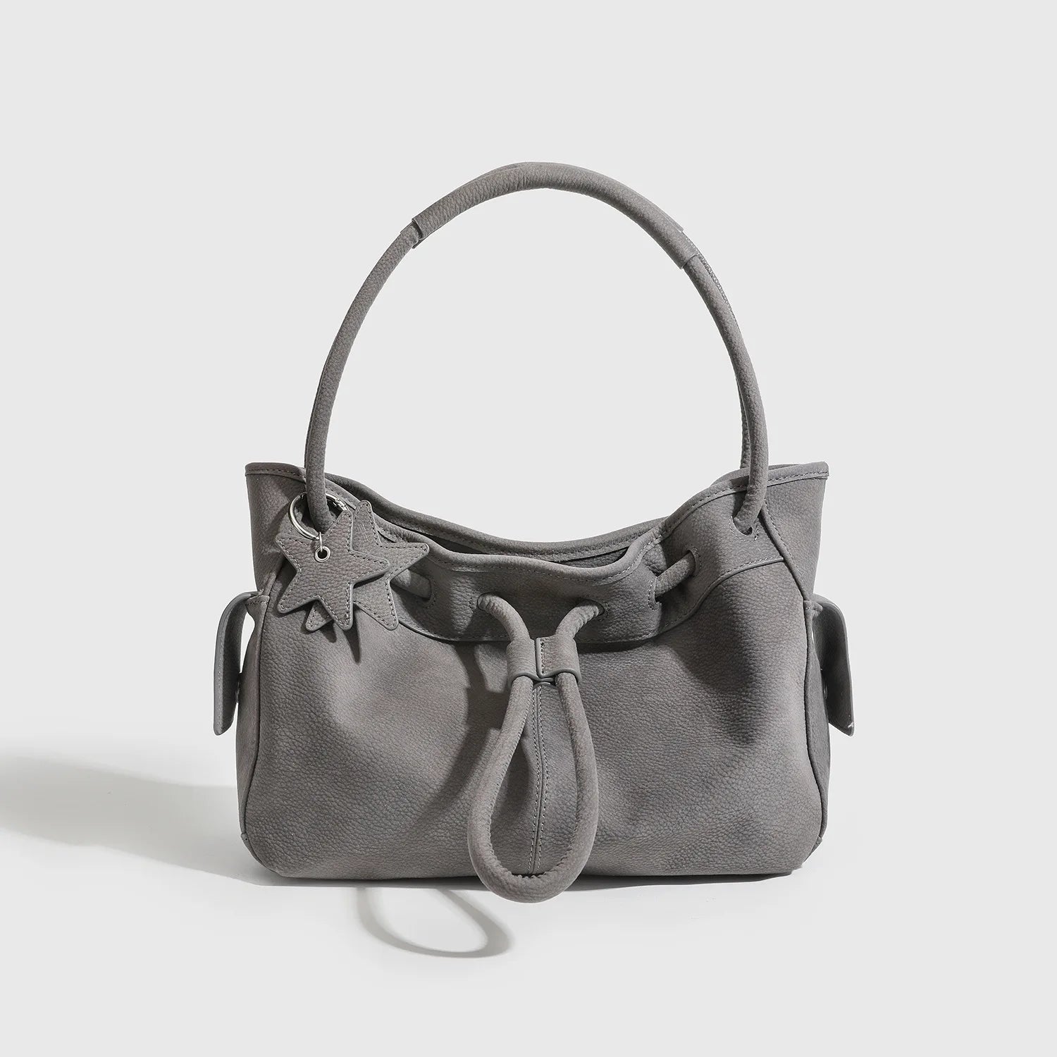 Grey textured leather designer shoulder bag with drawstring closure, star charm, and spacious commuting design.