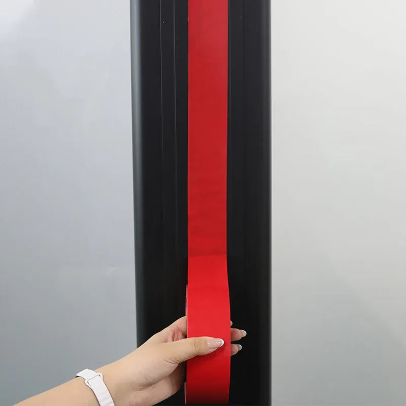 Red adhesive tape strip applied along the edge of a black surface