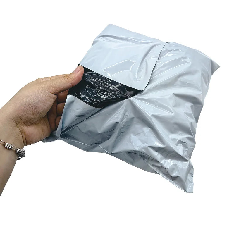 Light gray poly mailer shipping bag held open, heat-sealed edge visible