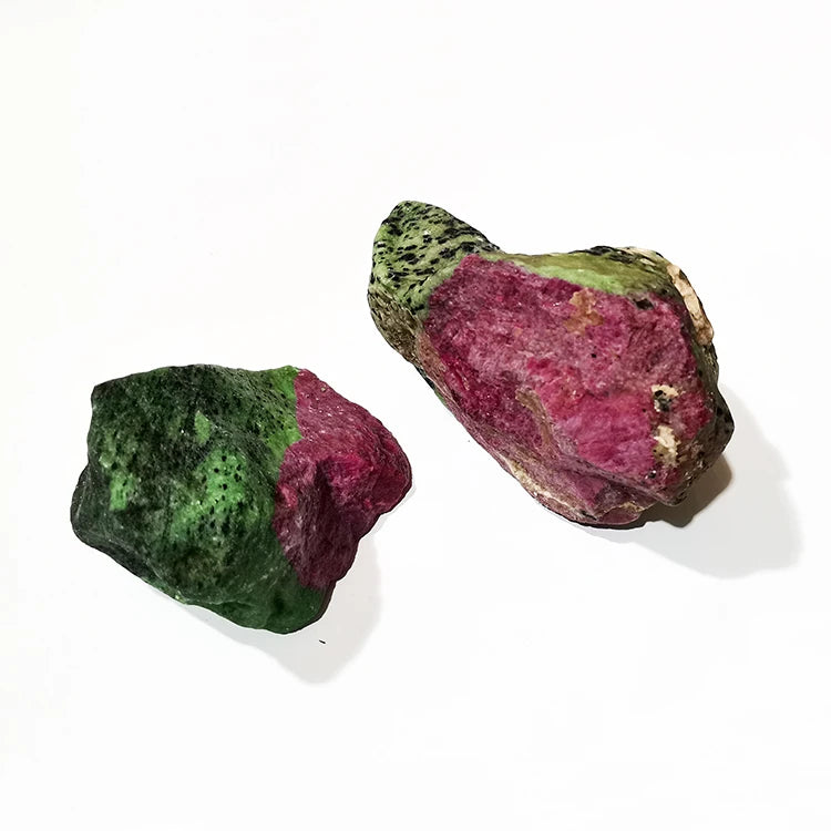 Two rough red and green quartz stones on a light background