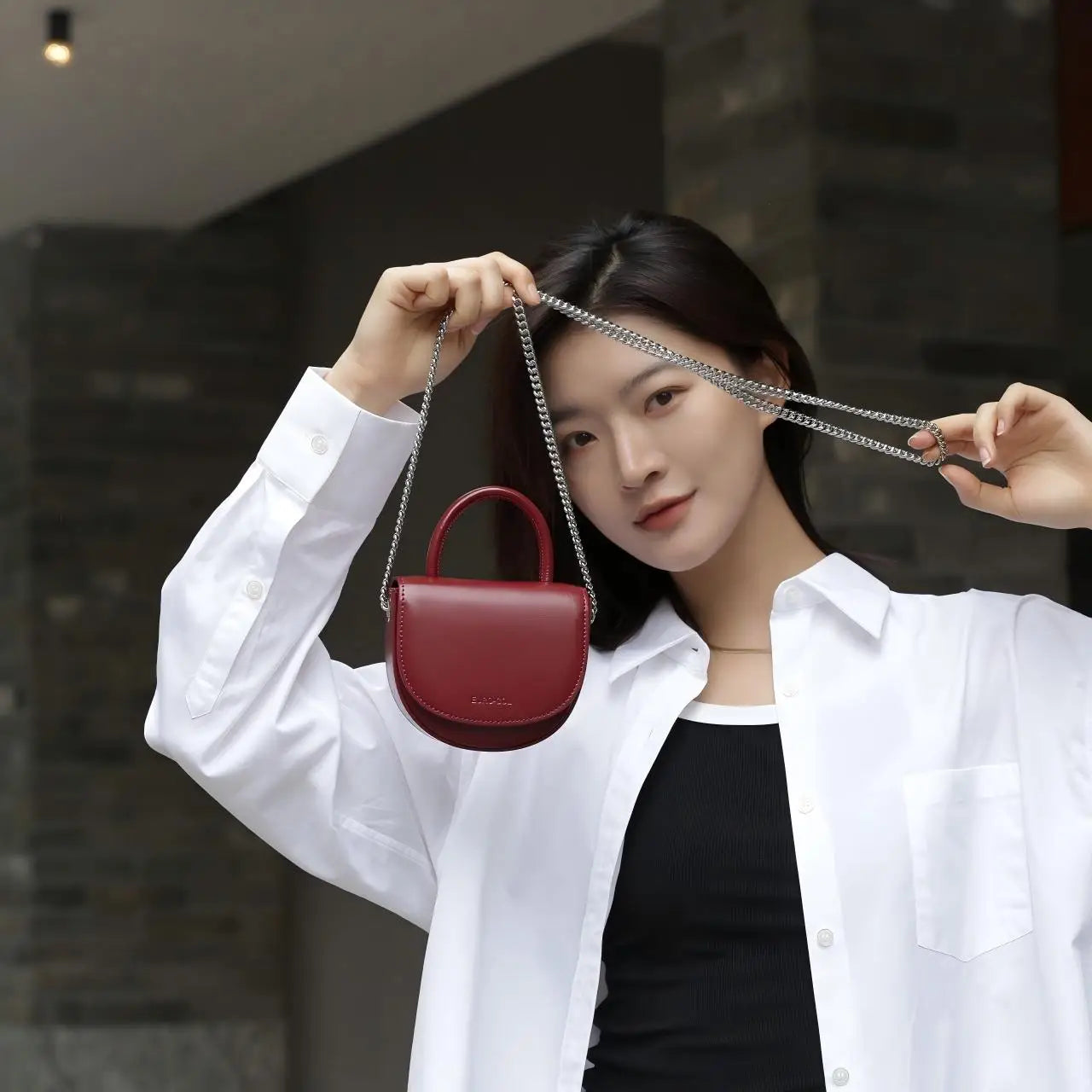 Burgundy cowhide leather mini clutch with silver chain strap and top handle, perfect for elegant evening wear.