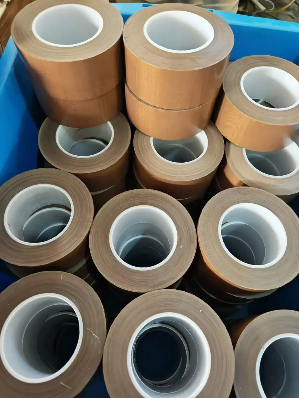 Multiple brown tape rolls with white inner rings stacked together