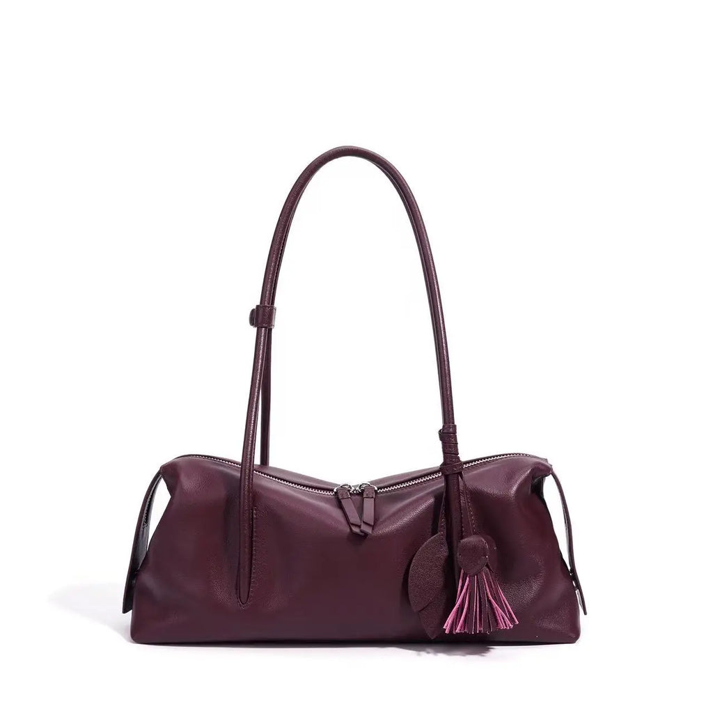 Burgundy genuine cowhide leather trunk shoulder bag with a zipper closure, adjustable strap, and decorative tassel.