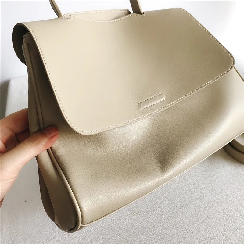 Minimalist beige leather designer handbag with a sleek flap closure, Korean-style simple messenger bag design.