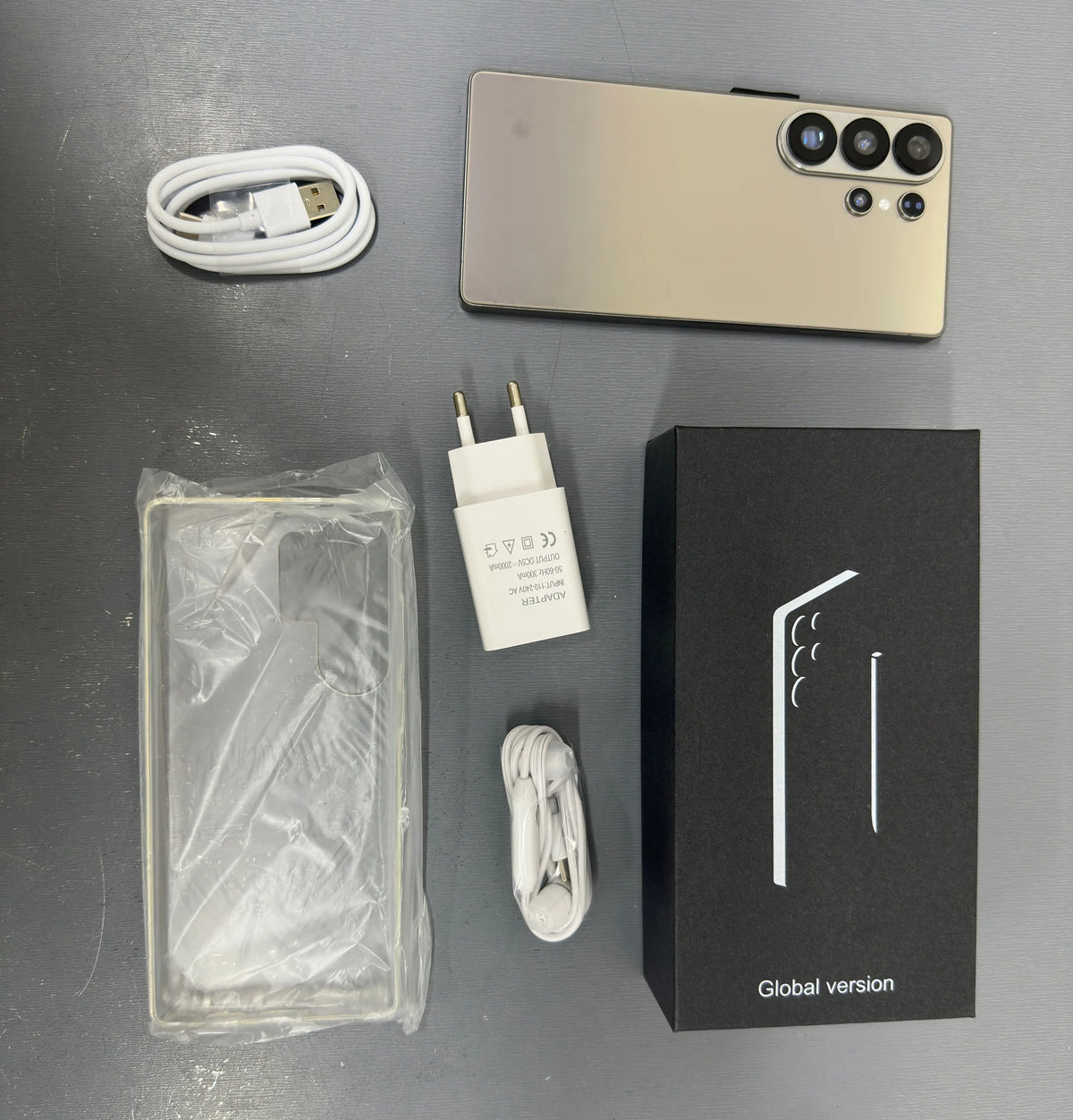 Smartphone with gold back, charger, cable, and global version box with phone case
