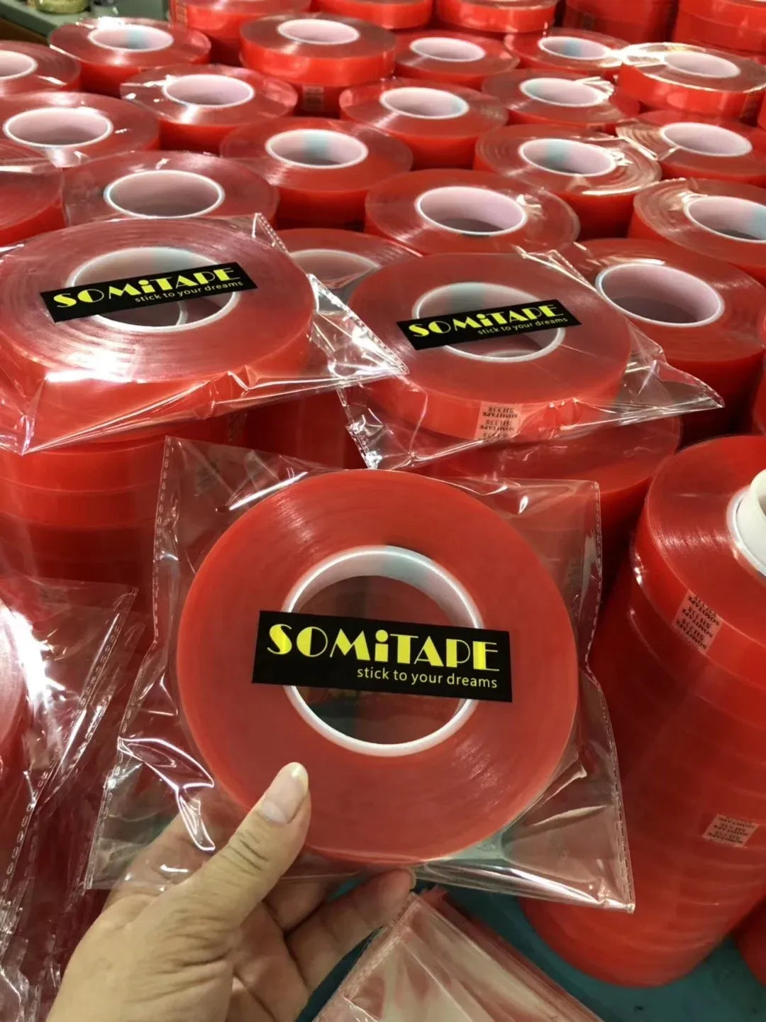 Red double-sided tape rolls in clear plastic bags, stacked together