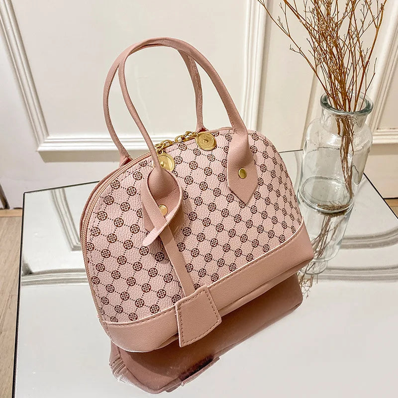 Pink designer shell handbag with clover monogram pattern, gold zipper hardware, and double handles for daily use.