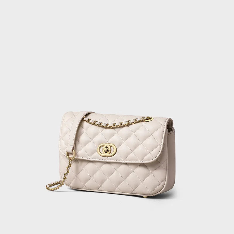 Beige quilted leather crossbody bag with gold chain strap and modern turn-lock flap closure.