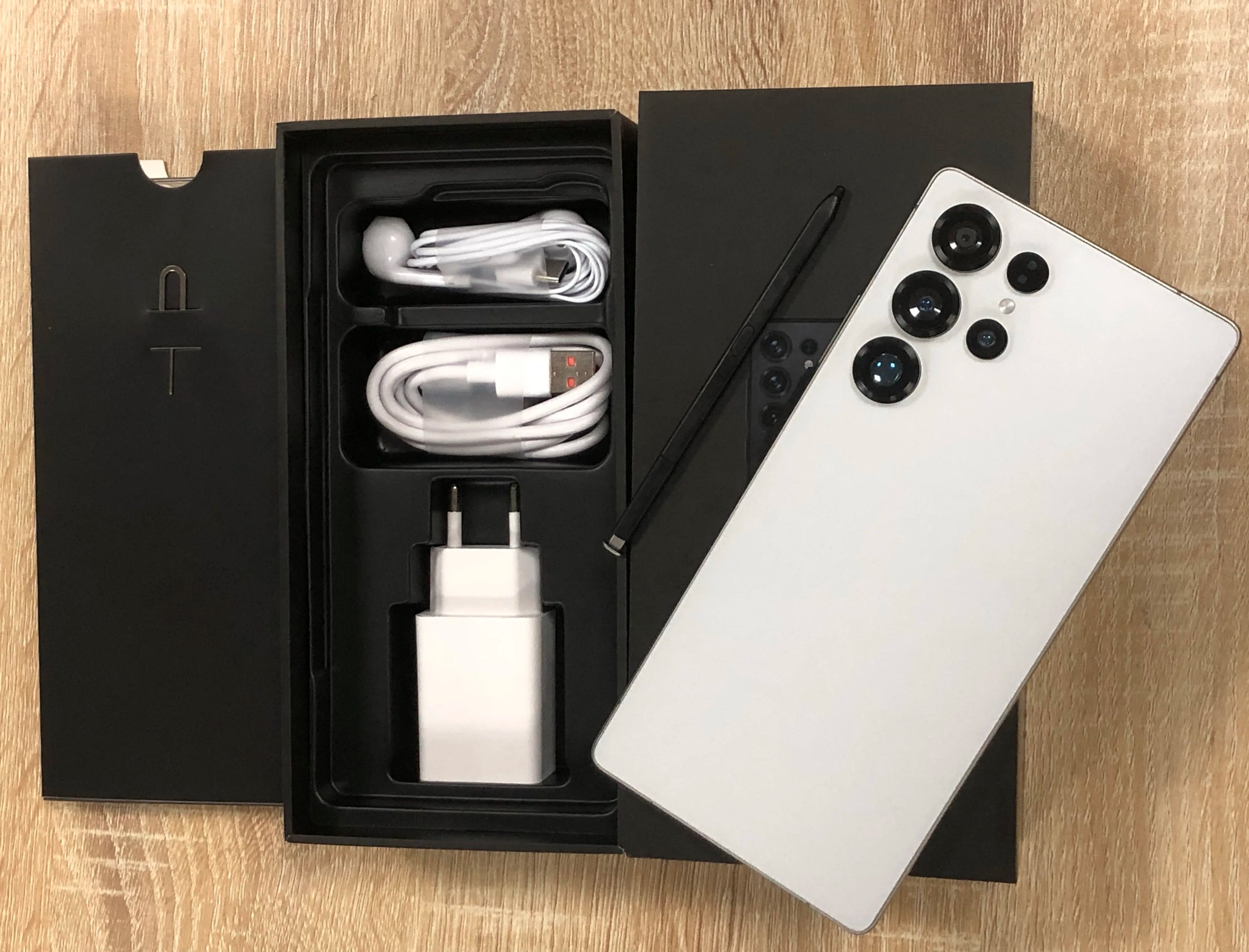 Android smartphone with silver back and quad rear cameras; box with cable and wall charger