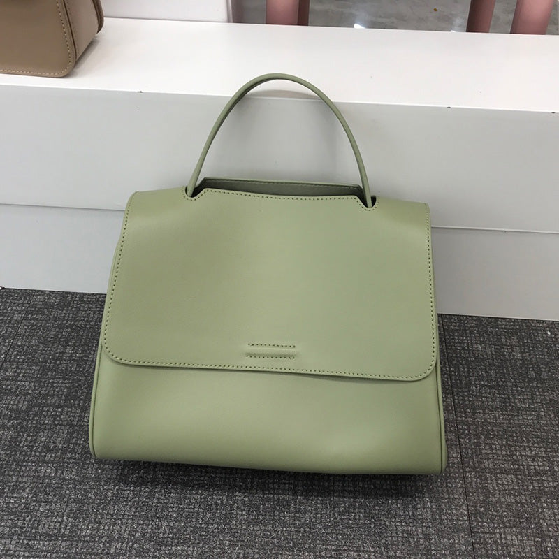 Sage green minimalist leather designer handbag with a top handle and structured flap messenger silhouette.
