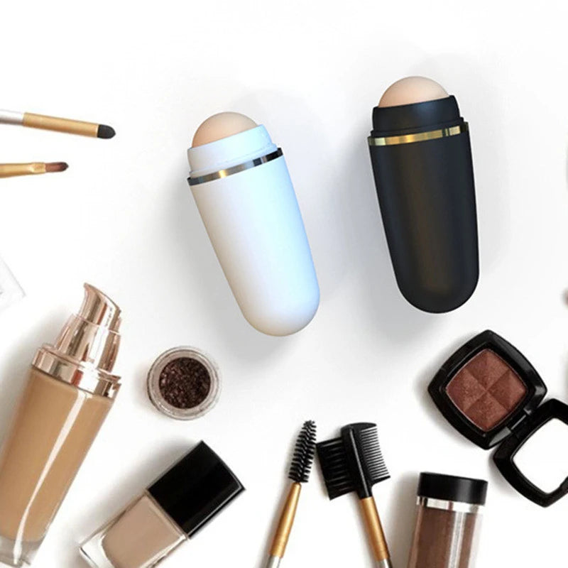 White and black volcanic stone face oil absorbing rollers surrounded by various makeup brushes and cosmetics.
