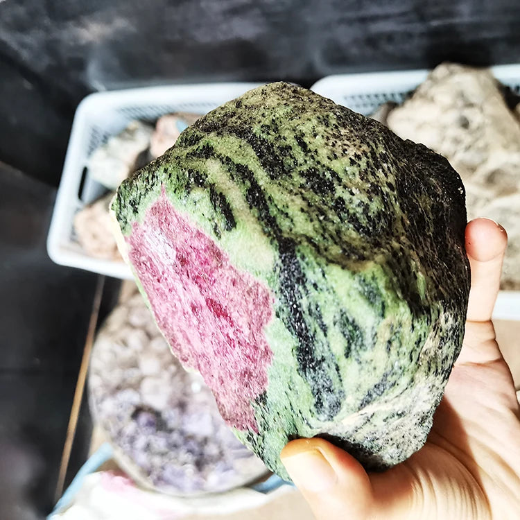 Handheld rough red-and-green quartz stone, speckled black matrix