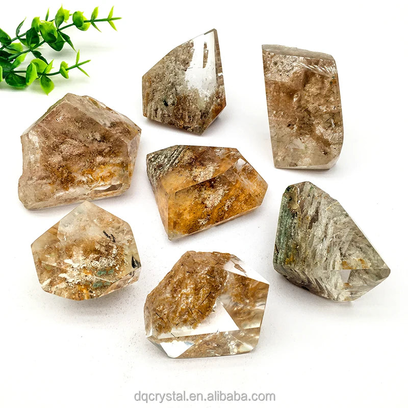 Assorted polished phantom quartz crystals: clear with brown-gold inclusions and one dark green piece